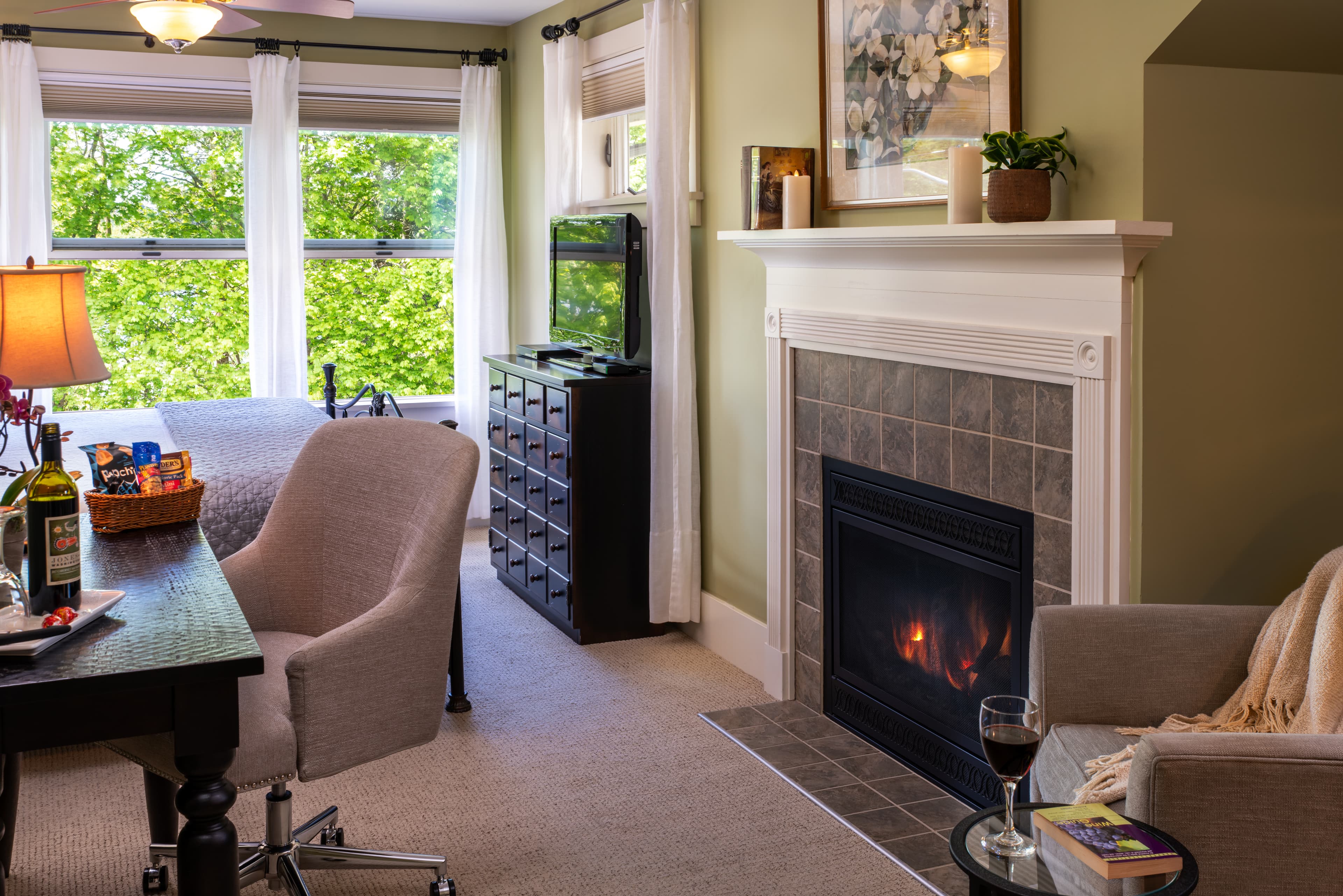 Cozy home office with a desk, chair, and shelves by a window with greenery view.