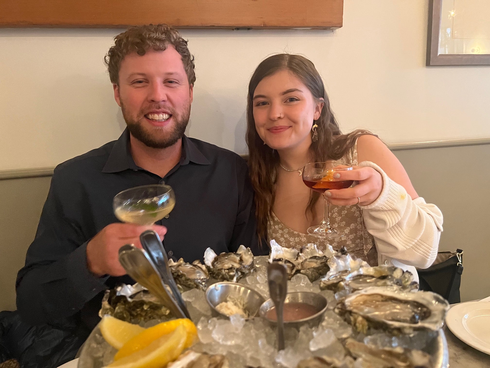 Man and woman  sitting behind tray of fresh oysters on ice