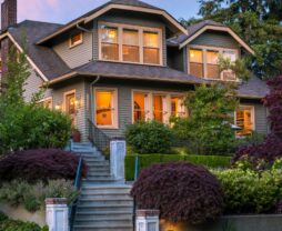 Greenlake Guest House exterior with lights on at sunset, surrounded by lush gardens and front steps in foreground